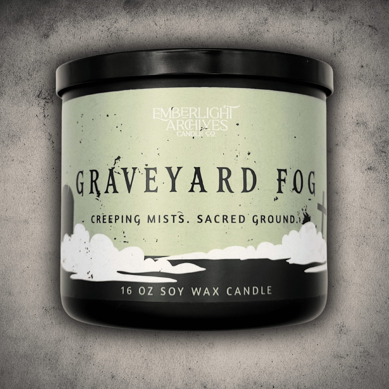16oz candle in a black jar labeled 'Graveyard Fog' by Emberlight Archives on a textured gray background
